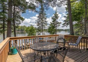 a table and chairs on a deck with a view of the water at Pinewood - Bouchard Shores Resort in Minocqua