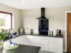 a kitchen with white cabinets and a black counter top at Stroma in Edderton