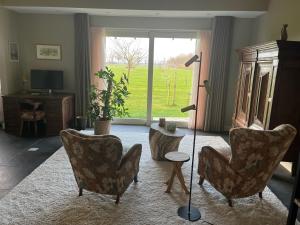 a living room with chairs and a table and a window at In de Hemmele bij Maria in Lievelde