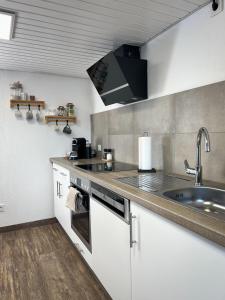 a kitchen with white cabinets and a sink at De Bookholt - Premium Ferienwohnung in Vreden