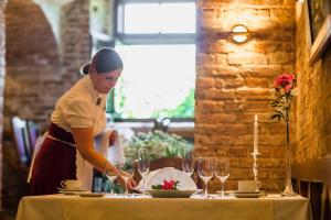 a woman is preparing a table with wine glasses at Birinu Castle in Bīriņi