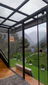 a glass room with a view of a garden at Kasol A-Frame Cottage in Kasol +6 photos
