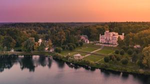 an aerial view of a large house next to a lake at Birinu Castle in Bīriņi