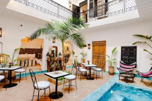 a restaurant with tables and chairs and a pool at Riad Taww'Ami in Marrakesh