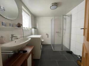 a white bathroom with a sink and a shower at Ferienhaus Leuchtturm in Dornum