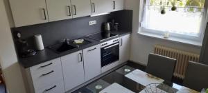 a kitchen with white cabinets and a black counter top at Ferienhaus Leuchtturm in Dornum