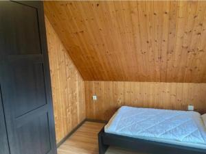 a bed in a room with a wooden ceiling at Ferienhaus Leuchtturm in Dornum
