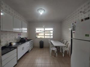 a kitchen with a table and a white refrigerator at Hostel Pantanal Em Florianópolis in Florianópolis