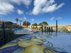 a table with a painting on it next to a pool at Ta' Cenc Residence Block C, Apt 4 in Sannat