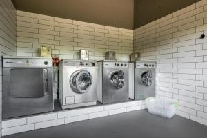 four washing machines are lined up in a laundry room at Bungalows Pirineus in Guils de Cerdaña