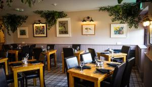 a restaurant with wooden tables and black chairs at Redmire Village Pub in Redmire