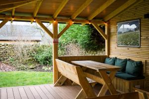 a wooden deck with a wooden table and a bench at Redmire Village Pub in Redmire