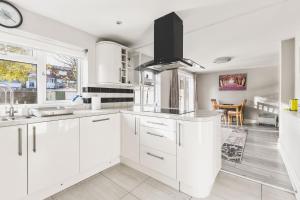 a white kitchen with white cabinets and a sink at Spacious 4BDR House with Parking by Heathrow in Hillingdon +28 photos