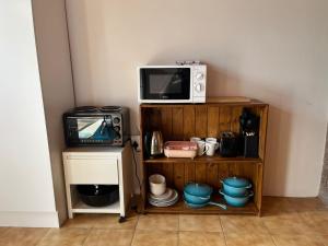 a microwave sitting on top of a wooden shelf next to a tv at Blue Moon Cozy Poolside Bachelor Flat in Bellville