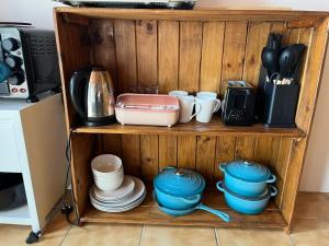 a wooden shelf with dishes and utensils on it at Blue Moon Cozy Poolside Bachelor Flat in Bellville