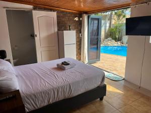 a bedroom with a bed and a door to a pool at Blue Moon Cozy Poolside Bachelor Flat in Bellville