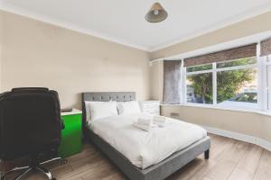 a bedroom with a bed and a desk and a television at Spacious 4BDR House with Parking by Heathrow in Hillingdon