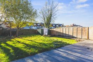 a grassy yard with a fence and a sidewalk at Spacious 4BDR House with Parking by Heathrow in Hillingdon