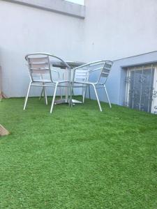 zwei Stühle und ein Tisch auf einer Terrasse mit Rasen in der Unterkunft Hello Zimmer in Brügg