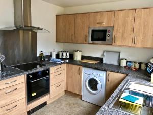 a kitchen with a washing machine and a microwave at Silver Birch Cottage in Aviemore