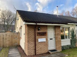 a small brick house with a white door at Silver Birch Cottage in Aviemore