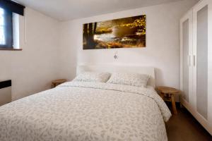 ein Schlafzimmer mit einem weißen Bett und einem Gemälde an der Wand in der Unterkunft Maison 25 in Houffalize