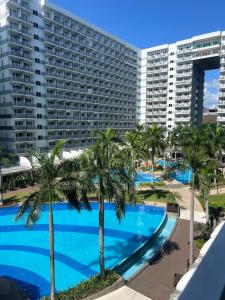a pool with palm trees in front of a large building at Shell Residences Tower A B in Manila