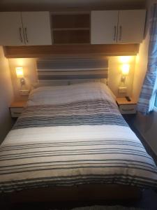 a large bed in a bedroom with two lamps at Lapwing 26 in Scratby +32 photos