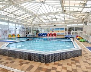 a large indoor swimming pool with a large tub in a building at Lapwing 26 in Scratby
