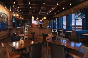 a restaurant with wooden tables and chairs and a bar at Hôtel Baker in Gaspé