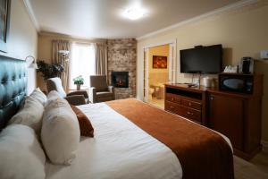 a hotel room with a large bed and a flat screen tv at Auberge l'Ambassadeur in Amqui