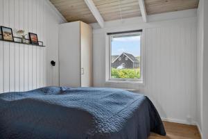 a bedroom with a blue bed and a window at 313-Harboore-Fourmivej-68 in Harboør