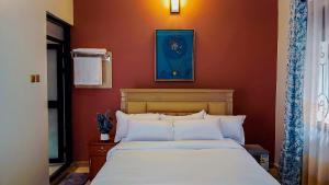 a bedroom with a bed with a blue picture on the wall at Cafe La Vida in Mbarara
