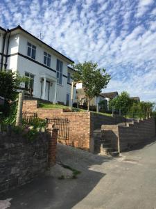 a white house with a brick retaining wall at Bryn Derwen in Rhayader