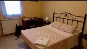 a bedroom with a bed with a checkered blanket and a window at Albergue Los Templarios in Terradillos de Templarios