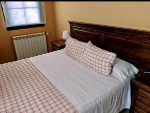 a bedroom with a bed with a checkered pillow and a window at Albergue Los Templarios in Terradillos de Templarios