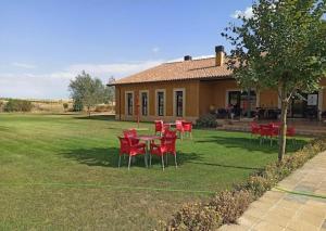 a house with red chairs and a table in the yard at Albergue Los Templarios in Terradillos de Templarios