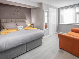 a bedroom with a large bed and an orange chair at The Ascot in Blackpool