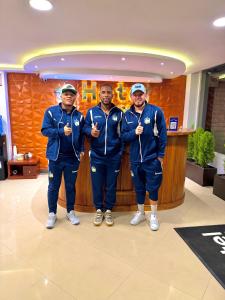 three men in blue uniforms standing in a lobby at Hotel Quitus Airport in Quito