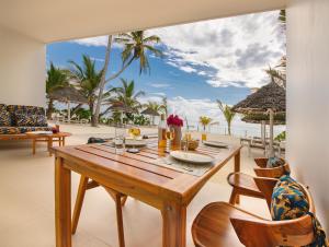 a dining room with a table and a view of the beach at Private Beach Front 2-Bedroom Apartment, Groundfloor in Kiwengwa