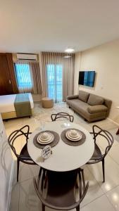 a living room with a table and chairs and a bed at Flat PRAIA de Camburi in Vitória