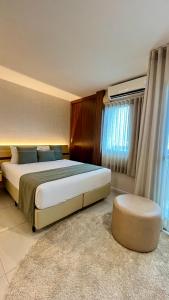 a bedroom with a large bed and a ottoman in it at Flat PRAIA de Camburi in Vitória +36 photos