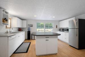 a kitchen with white cabinets and a black refrigerator at Suite and Simple in Ucluelet