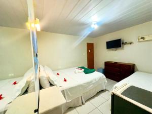 a hotel room with two beds and a television at Pousada São Silmares in Fernando de Noronha