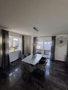 a dining room with a table and chairs and windows at Haus Katja in Büdelsdorf