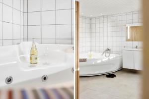 a bathroom with a white tub and a bottle of wine at 347-Harboore-Slettevej-71 in Harboør +37 photos