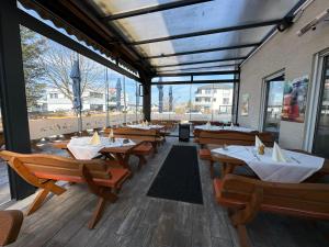 a restaurant with wooden tables and chairs and windows at La Casa Motel in Schaafheim