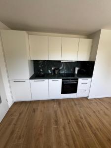 a kitchen with white cabinets and a wooden floor at Karla in Torgelow