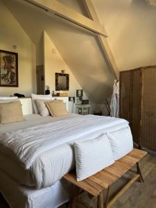 a bedroom with a large white bed with a wooden bench at L'Orée du Mont proche du mont saint Michel in Pontorson