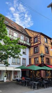 a building with tables and an umbrella in front of it at Bel appartement hyper centre in Sélestat